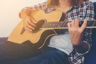 Midsection of woman playing guitar