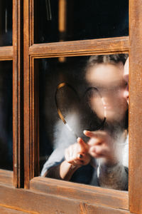 Portrait of young man holding glass window