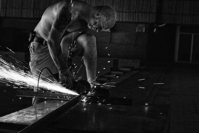 Side view of mature worker cutting metal in factory