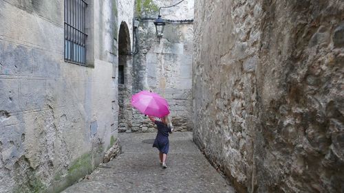 Rear view of woman with pink umbrella in city