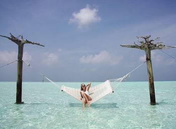 Young woman relaxing in hammock over sea at beach