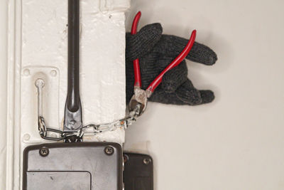 Cropped hand of burglar cutting chain on door with pliers 