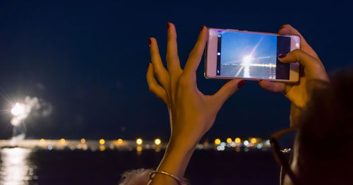 Close-up of woman photographing illuminated smart phone at night