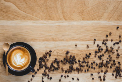 Directly above shot of cappuccino and coffee beans on wooden table