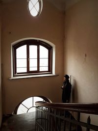 Woman standing against window in building