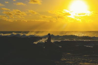 Silhouette woman standing on beach against sky during sunset