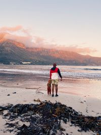 Father and son enjoying the sunset at hout bay beach, cape town. 