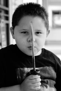 Portrait of boy holding knife sitting at home