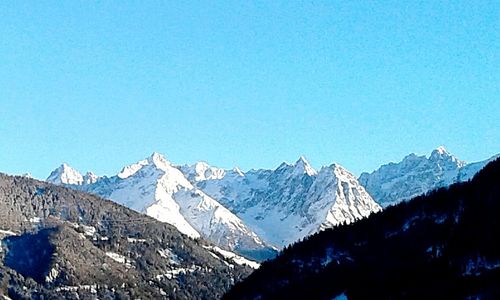 Scenic view of snowcapped mountains against clear blue sky