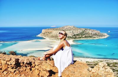 Woman wearing sunglasses sitting against sea