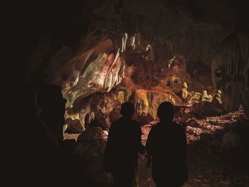 Rear view of people standing in cave
