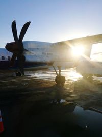 Silhouette airplane on airport against sky on sunny day