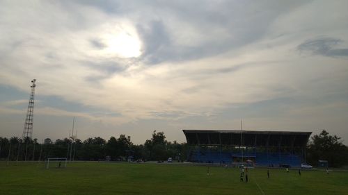 People playing soccer on field against sky