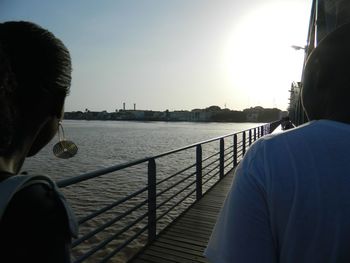 Rear view of man and woman on railing against river