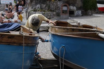 Man painting boat moored at beach