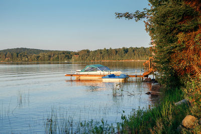 Summer on lake cottage. small yacht boat by wooden dock pier on lake at sunset. 