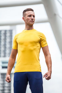 Full length of young man standing against yellow wall