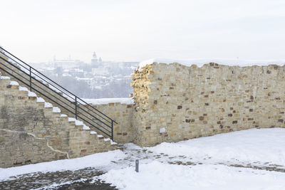 Snow covered wall against sky in city