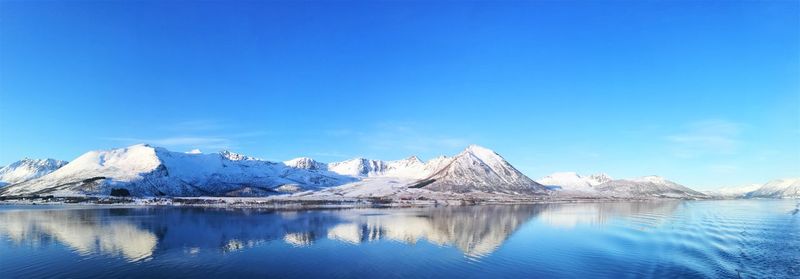 Scenic view of lake and mountains against blue sky