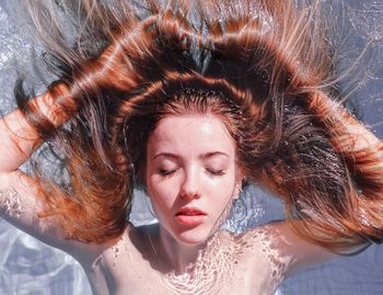 High angle view of teenage girl with eyes closed floating on water