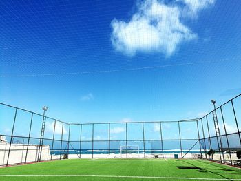 Scenic view of soccer field against blue sky