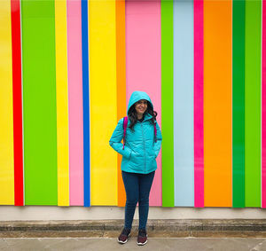 Full length of woman standing against multi colored wall