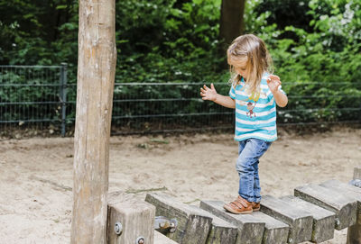 Full length of girl walking on wooden bridge at park