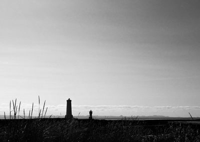 Lighthouse on field against clear sky