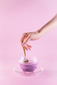 Midsection of woman holding drink against pink background