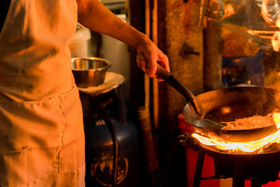 Midsection of chef preparing food in commercial kitchen