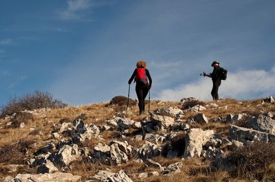 Rear view of man walking on mountain against sky