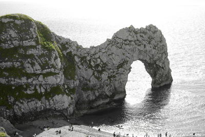 Rock formation by sea against sky