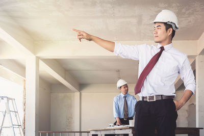 Confident engineer with colleague standing at construction site