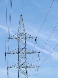 Low angle view of electricity pylon against blue sky