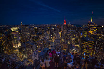 High angle view of people on terrace in illuminated city at night