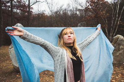 Woman with scarf standing against trees in forest