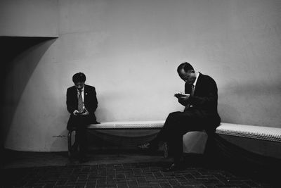 Man using mobile phone while sitting on wall