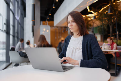 Woman using laptop sitting at cafe