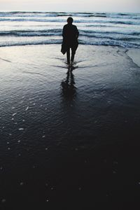 Rear view of silhouette man standing on beach