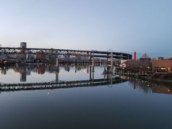 Reflection of illuminated buildings in river against clear sky