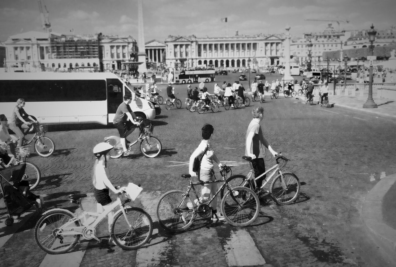 land vehicle, bicycle, transportation, mode of transport, large group of people, street, men, building exterior, architecture, parked, parking, city, built structure, car, city life, lifestyles, riding, person, motorcycle