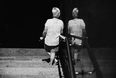 Rear view of couple walking on road at night