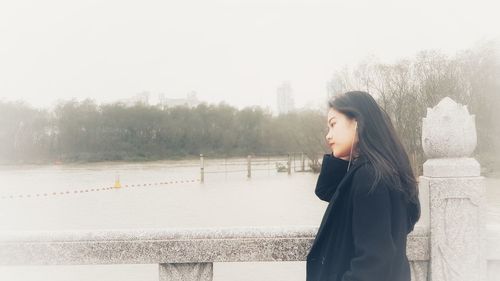 Side view of young woman standing in park during winter