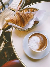 High angle view of coffee with croissant on table in cafe