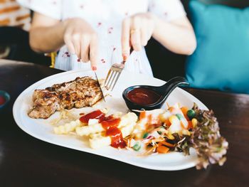 Midsection of woman eating food at restaurant