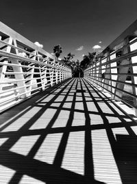 Shadow of railing on footbridge against clear sky