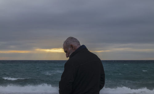 Adult man in winter clothes on beach during sunset. almeria, spain