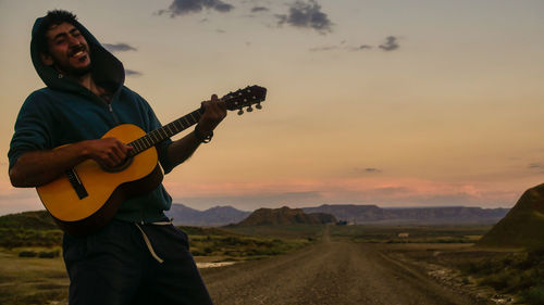 Man playing guitar at sunset