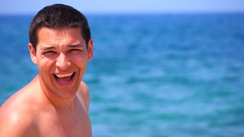 Close-up portrait of smiling man against sea