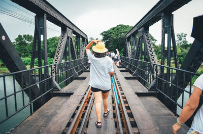 Rear view of woman walking on railroad tracks